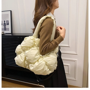 Détail d'un sac à bandoulière matelassé beige avec une texture en nylon plissé