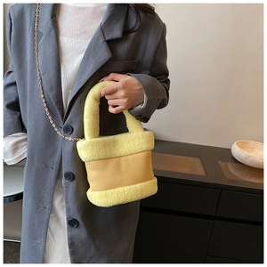 Detail of yellow plush bucket bag featuring faux fur textures and gold chain strap