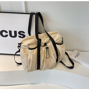 Detail view of functional beige nylon tote with drawstring pockets and adjustable straps