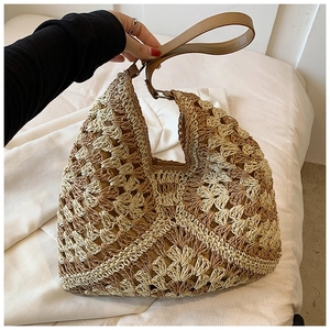 Close-up of woven straw tote bag with contrast geometric patterns and leather handles