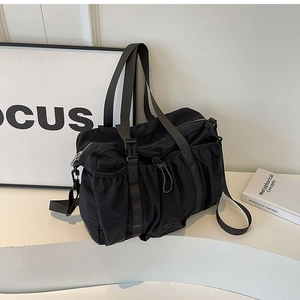 Detail of black nylon functional bag featuring side drawstring pockets and clip buckle straps