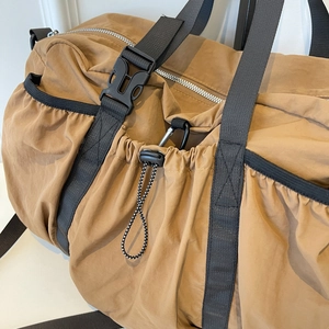 Close-up of brown nylon travel bag with heavy-duty webbing, metal hooks and drawstring detail