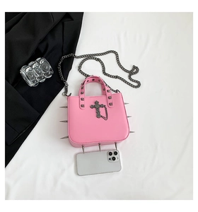 Detail of pink gothic handbag featuring silver rivets, metal cross, and chain strap