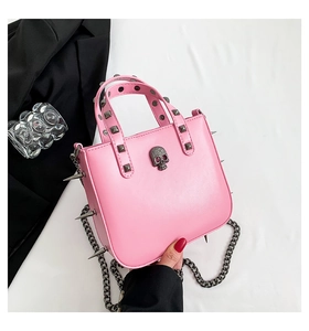 Detail of pink gothic handbag with skull buckle, metal studs, and sharp side spikes