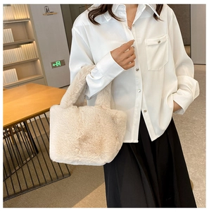 Plush cream bucket bag made of soft faux fur held by a model in a warm indoor setting