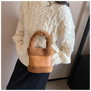 Close-up of brown plush and leather bucket bag with a golden chain and fuzzy handle