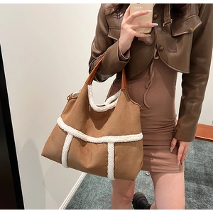 Close-up of brown suede tote bag with white fleece trim and leather handles