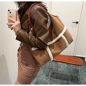 Detail of a large brown suede tote with white faux fur trim and leather handles