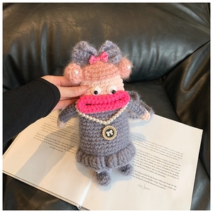 Détail d'une poupée au crochet faite main avec collier de perles sur un livre