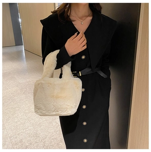 Detail view of a soft cream plush handbag styled with a black dress in a modern interior
