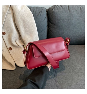 Detailed view of a dark red leather baguette bag with vintage gold metal hardware buckles
