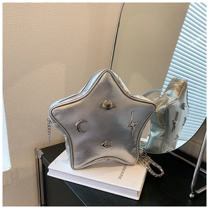 Detail of silver star-shaped crossbody bag with metallic moon and planet charms