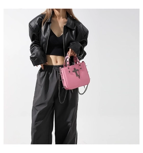 Pink gothic handbag detail with metallic rivets, cross charm, and metal chain strap