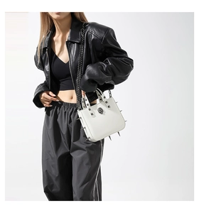 Detail of white gothic handbag with silver metal spikes and skull hardware