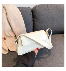Close-up of white leather square shoulder bag with gold ring buckle and wide strap