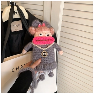 Détail d'un sac singe au crochet fait main avec nœud rose et collier de perles élégant