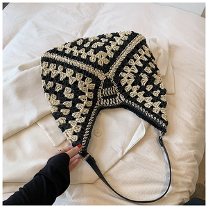 Detail of hand-crocheted hobo bag featuring black and beige patterns and leather strap