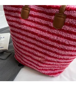 Détail du sac fourre-tout rayé en fausse fourrure rose et rouge avec anses en similicuir