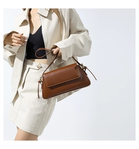 Detail view of brown leather shoulder bag with fine stitching and adjustable strap
