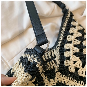 Close-up of black leather shoulder strap and silver metal buckle on woven straw bag