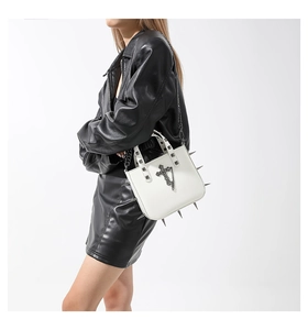 Detailed side view of white gothic bag with silver spikes and cross metal hardware