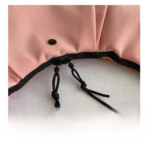 Detalle de las cremalleras dobles suaves en el bolso de hombro de nailon rosa claro