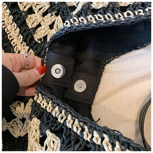 Detail of metal magnetic clasp and black lining on woven black and white checkered bag