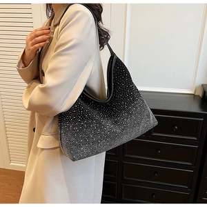 Detalle del bolso hobo negro con diamantes de imitación al hombro en un ambiente interior