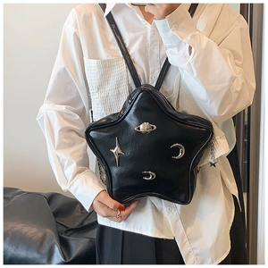 Detail showing the star-shaped black faux leather bag with Saturn-style metal charms