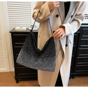 Detalle del bolso hobo con pedrería degradada en blanco y negro sostenido por una modelo