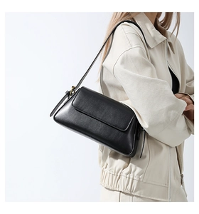 Minimalist black leather underarm bag with flap design shown on a model's shoulder