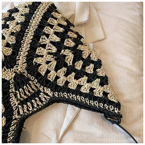 Detailed close-up of the black and cream crochet woven texture and leather strap joints