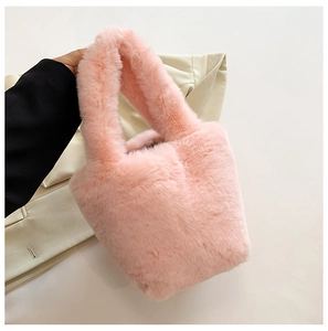 Detail of soft pink faux fur bucket bag featuring a thick plush handle and fluffy texture