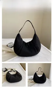 Primer plano de bolso bandolera de nailon negro con textura plisada y cordón ajustable
