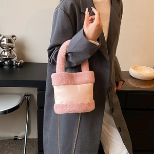 Pink plush patchwork bucket bag with metal chain strap shown on a model in gray blazer