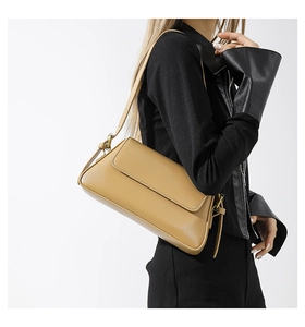 Close-up of khaki square shoulder bag with adjustable bronze metal buckle and leather strap
