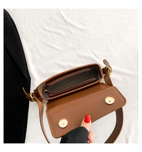 Detail of small brown leather bag interior showing zipper pocket and magnetic snap button