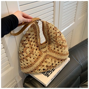 Detail of hand-woven straw hobo bag with brown leather strap and contrast color stitching