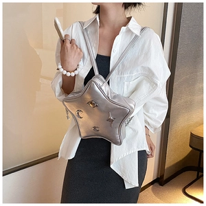Detail of silver star-shaped backpack with cosmic charms worn on shoulder by a model