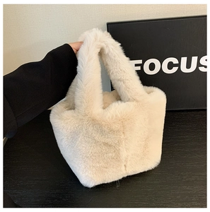 Detail view of a beige faux fur bucket bag with a soft texture and plush handles for autumn