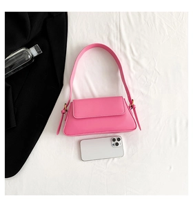 Detail view of a bright pink baguette bag showing its compact size next to a smartphone
