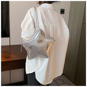 Silver star-shaped crossbody bag with metallic Y2K moon and planet charms on white shirt