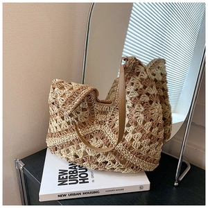 Detail of hollow crochet straw tote bag with brown leather strap and contrast weaving