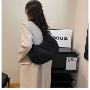 Bolso hobo minimalista de nailon negro con textura plisada mostrado en una modelo