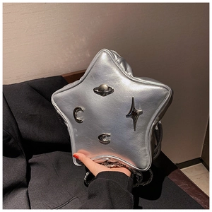 Detail of silver star-shaped crossbody bag with cosmic metallic moon and planet charms