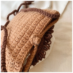 Détail macro du sac en tricot kaki avec franges marron foncé et texture tissée gaufre