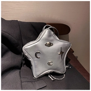 Detail of silver star-shaped leather bag featuring cosmic metal charms and chain strap