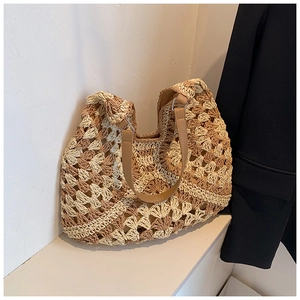 Close-up of bohemian woven straw tote bag featuring contrast stitching and leather handles