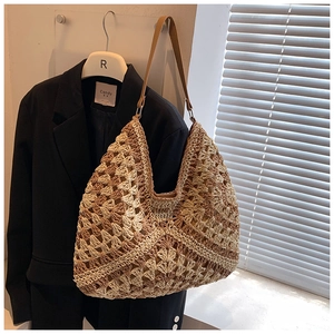 Detail of hand-woven straw tote with hollow rhombus pattern and brown leather strap
