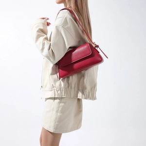 Minimalist red leather baguette shoulder bag shown on model in a stylish side view